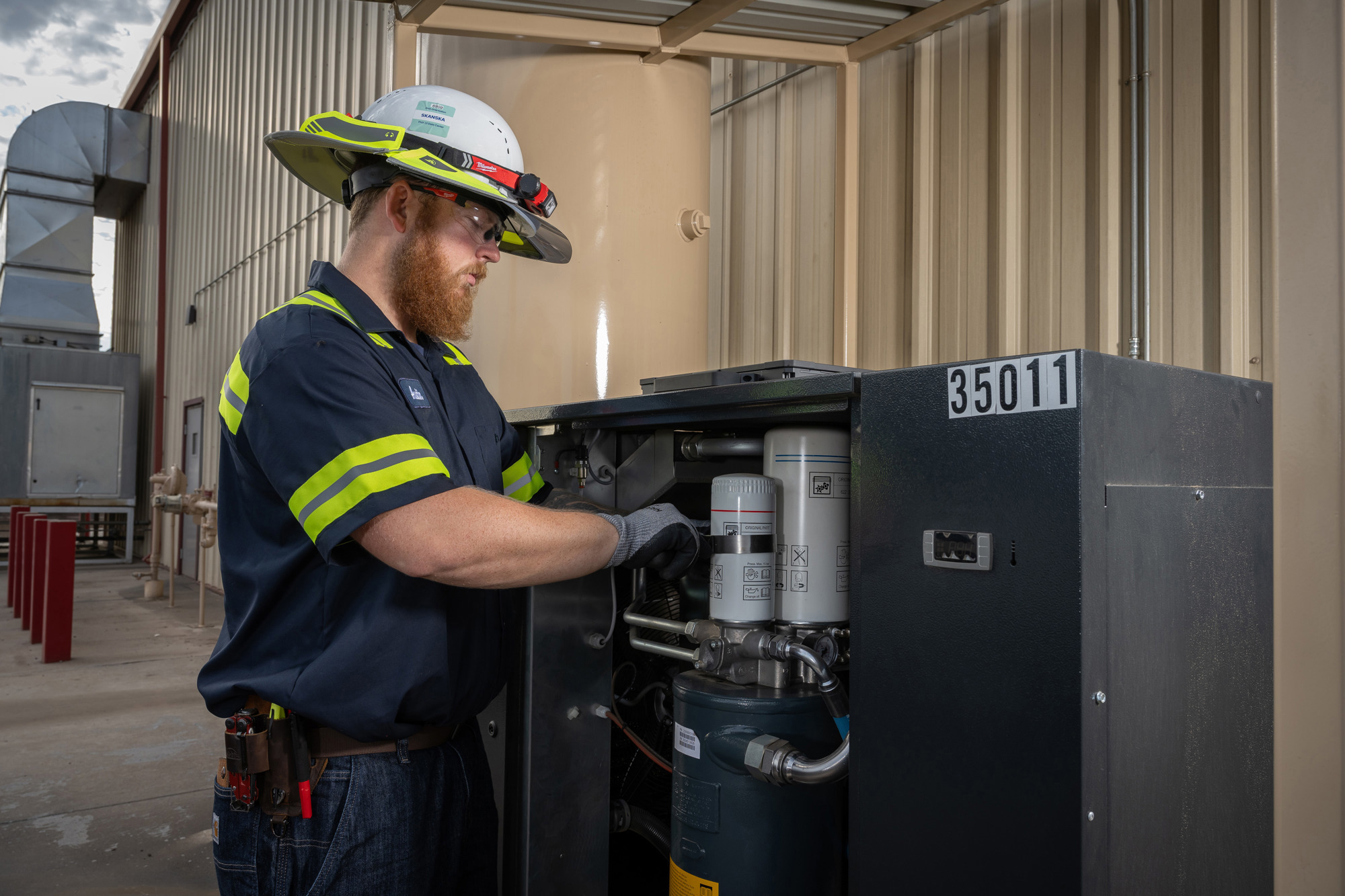 Technician in full PPE working on an air compressor cabinet